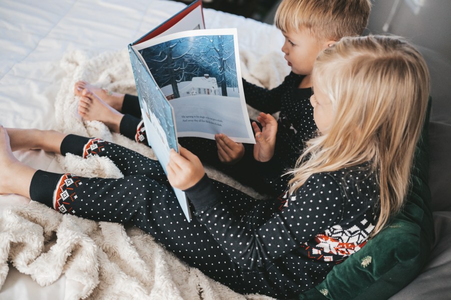 two kids in pajamas reading The Night Before Christmas